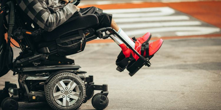 Person in a wheelchair practicing mindfulness outdoors, using a fidget ring, symbolizing anxiety relief and emotional wellness while living with a physical disability.
